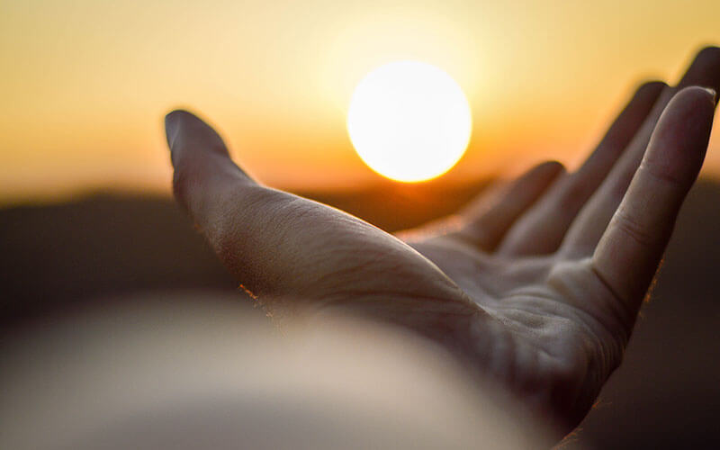 Hand reaching out to hold the sun